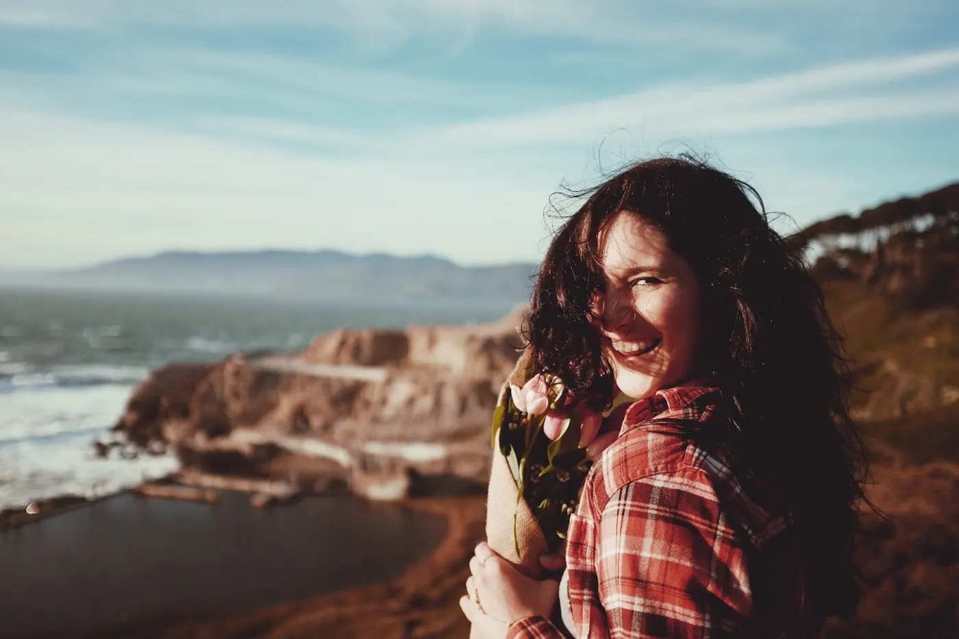 Shannon Bryson smiling with flowers beside the ocean